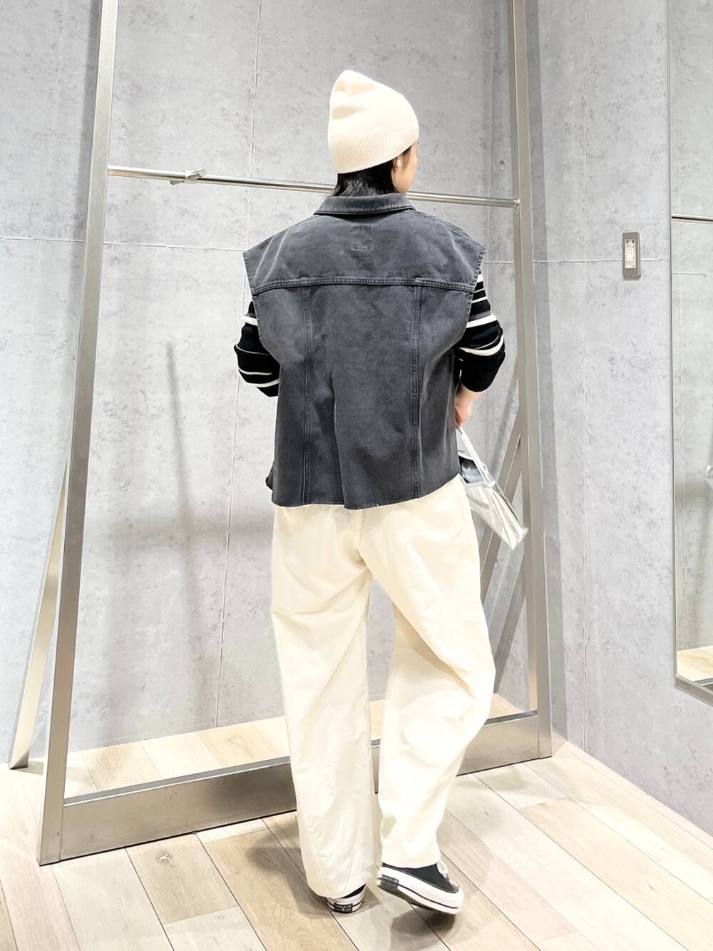 シルバー系のハンドバッグ、グレー系のベスト、ホワイト系のその他パンツを着用したレディースの冬コーディネートの6枚目の写真