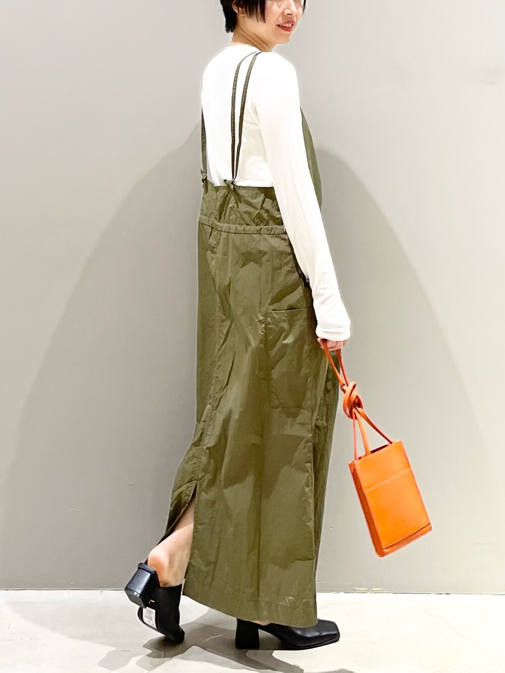 グリーン系のワンピース、オレンジ系のバッグ、ブラック系のサンダルを着用したレディースの春コーディネートの4枚目の写真