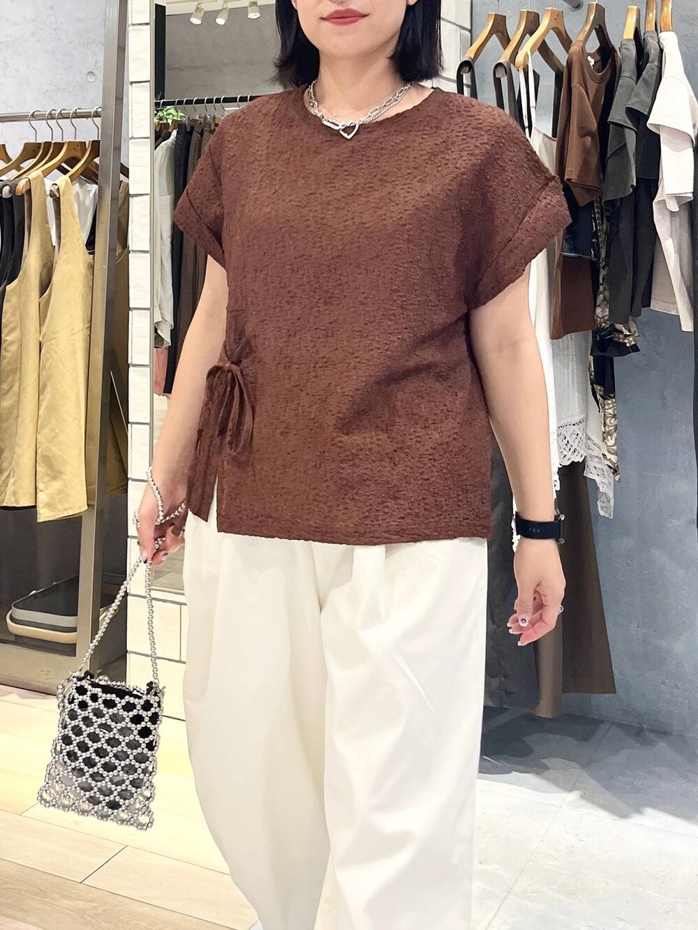 シルバー系のショルダーバッグ、ブラウン系のTシャツ/カットソー、ホワイト系のその他パンツを着用したレディースの夏コーディネートの2枚目の写真