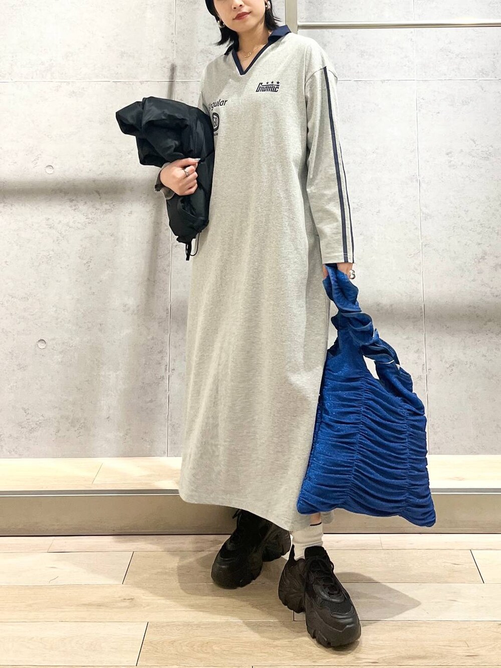 ブラック系のスニーカー、ブルー系のトートバッグ、ブラック系のベストを着用したレディースの冬コーディネートの7枚目の写真