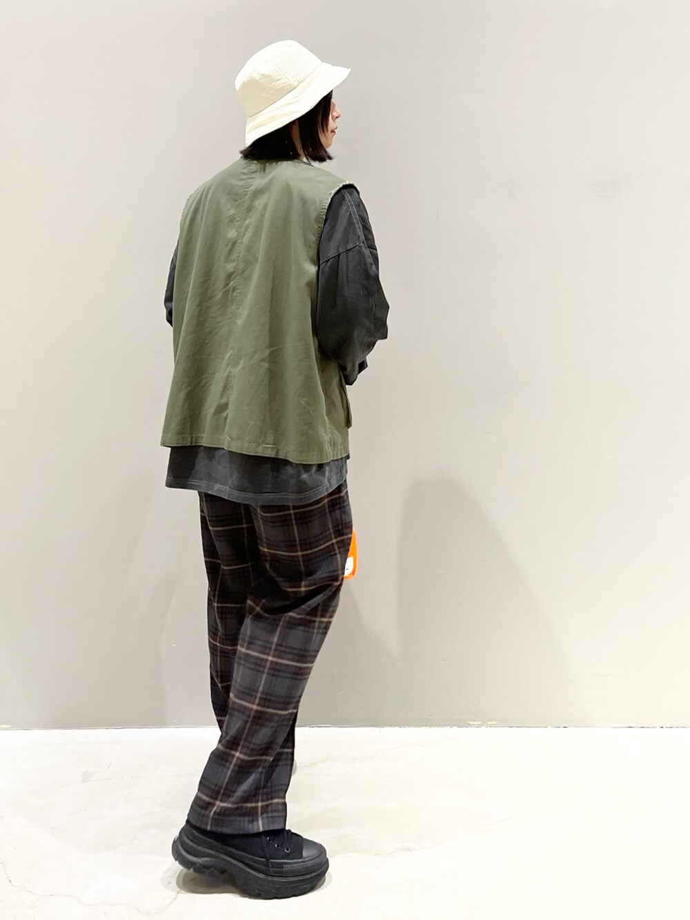 ブラウン系のスラックス、ブラック系のスニーカー、グリーン系のジャケット/アウターを着用したレディースの春コーディネートの3枚目の写真