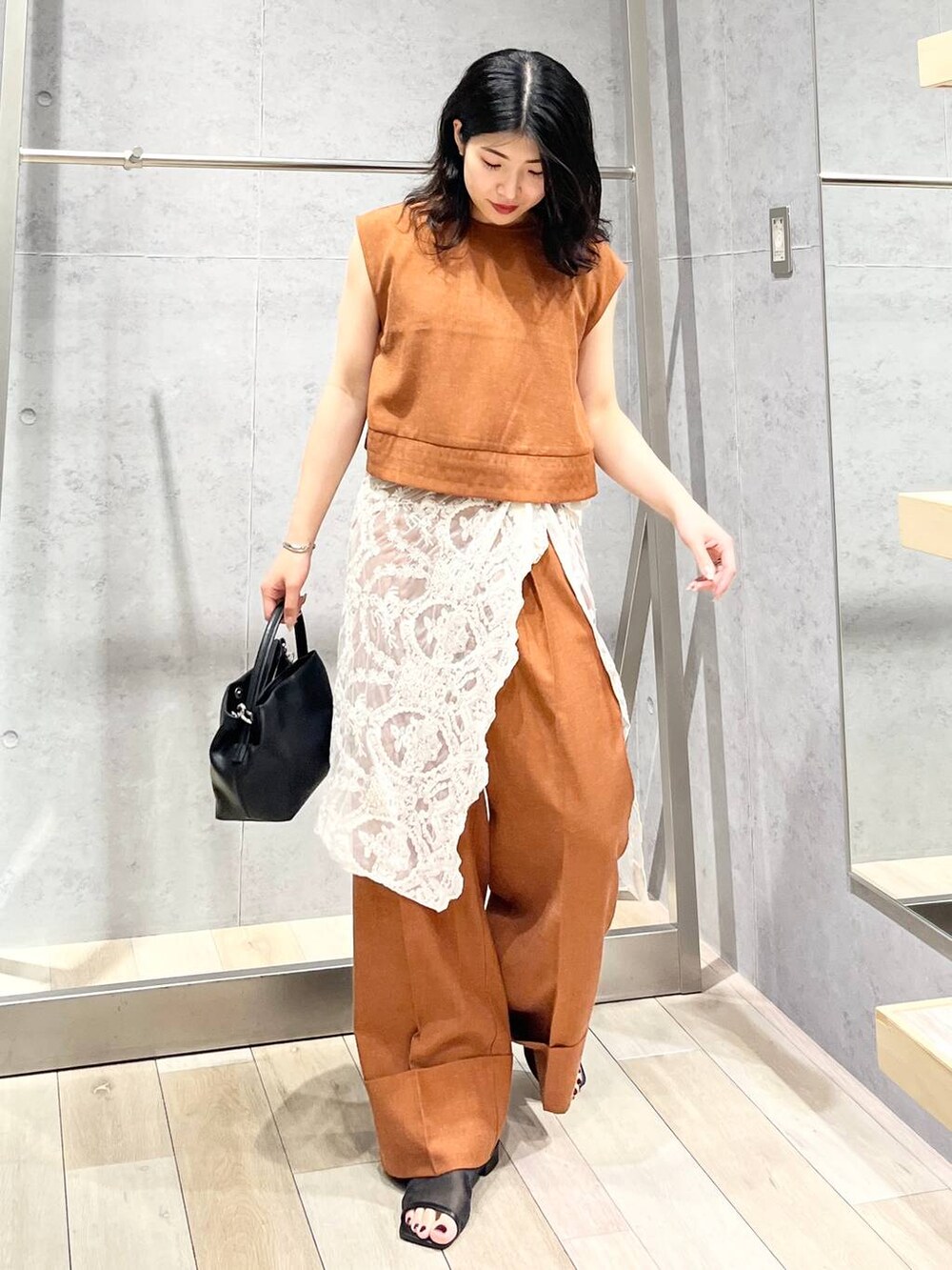 ブラック系のサンダル、オレンジ系のシャツ/ブラウス、ブラック系のショルダーバッグを着用したレディースの夏コーディネートの6枚目の写真