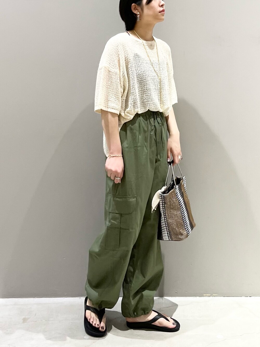 ブラック系のサンダル、ブラック系のトートバッグ、ホワイト系のニット/セーターを着用したレディースの夏コーディネートの7枚目の写真