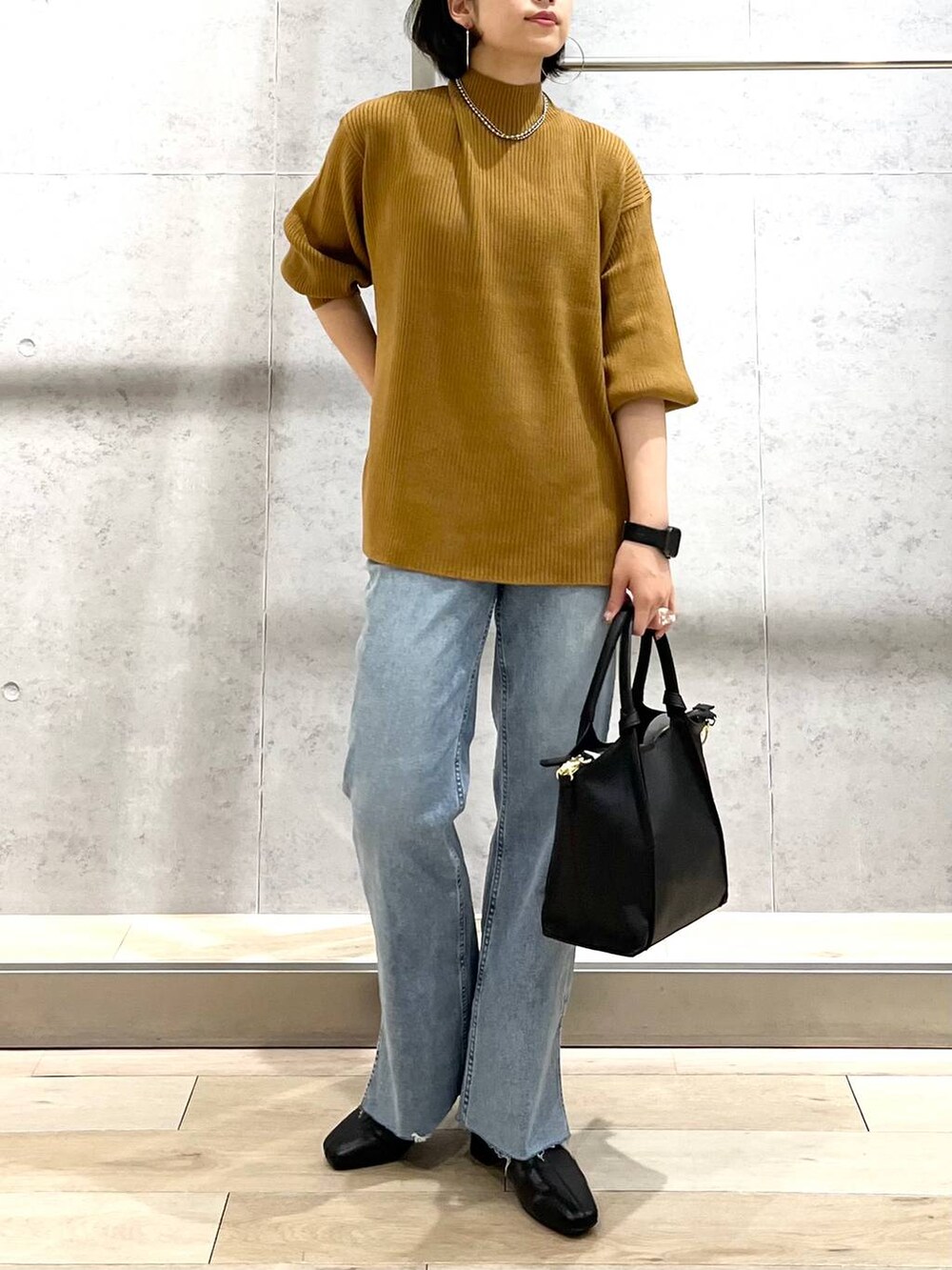 ブラウン系のニット/セーター、ブルー系のデニムパンツ、ベージュ系のショルダーバッグを着用したレディースの秋コーディネートの7枚目の写真