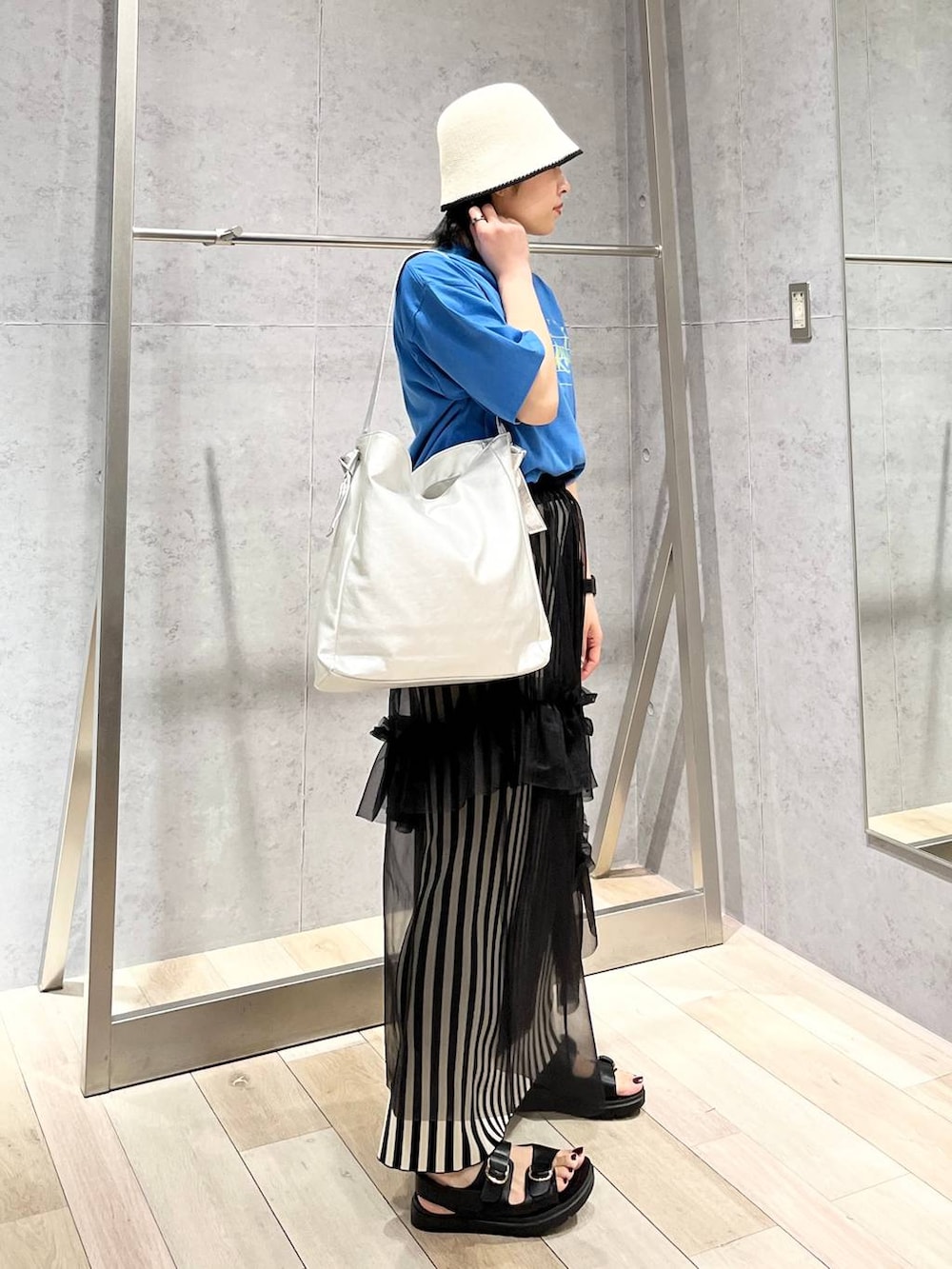 ホワイト系のスカート、ブルー系のTシャツ/カットソー、ブラック系のサンダルを着用したレディースの春コーディネートの4枚目の写真