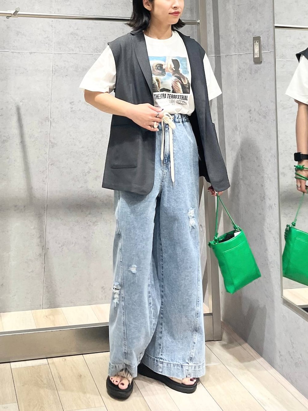 ベージュ系のサンダル、ブルー系のデニムパンツ、グリーン系のショルダーバッグを着用したレディースの夏コーディネートの2枚目の写真
