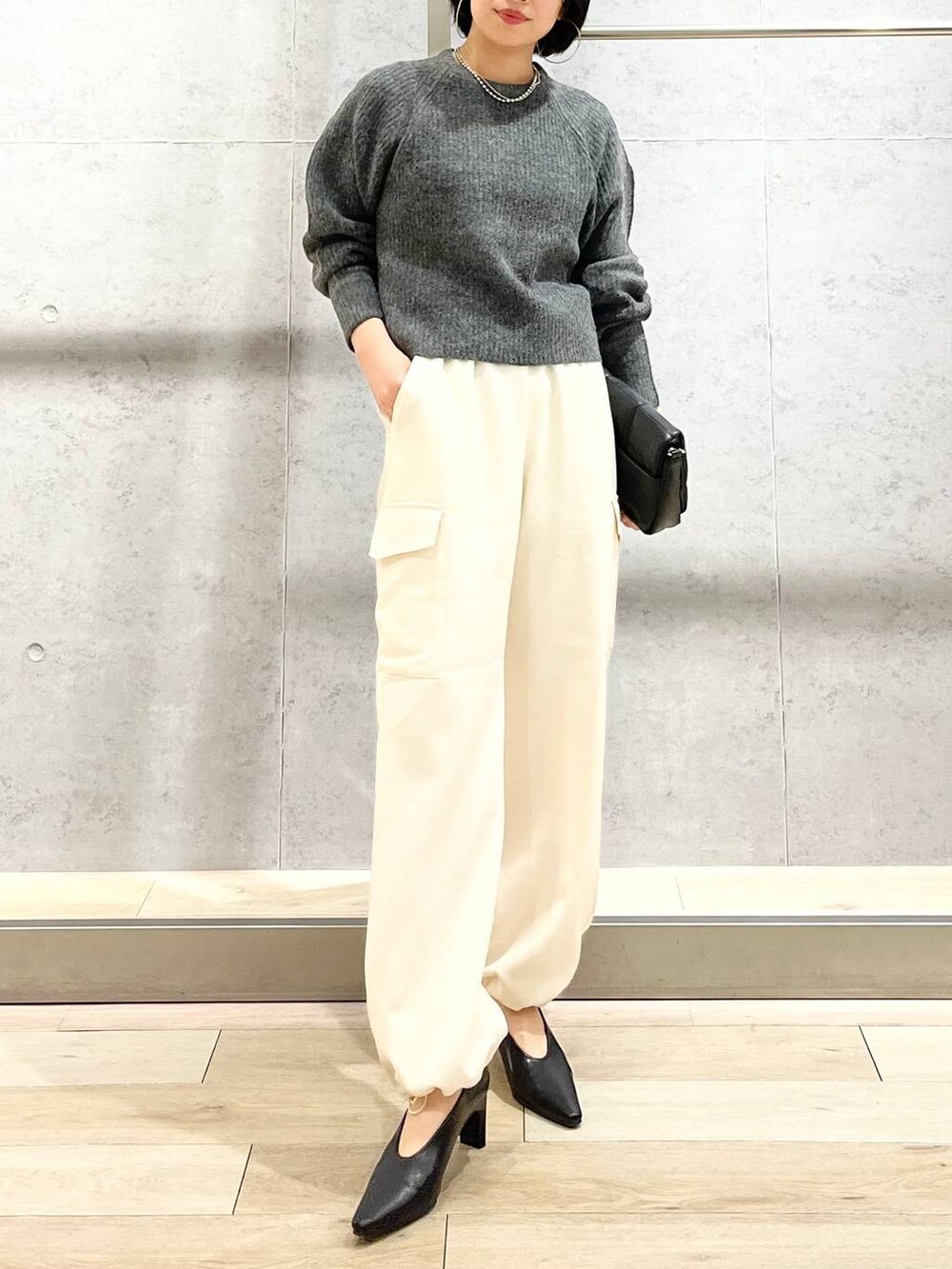 ブラック系のショルダーバッグ、ブラック系のパンプス、グレー系のニット/セーターを着用したレディースの秋コーディネートの5枚目の写真