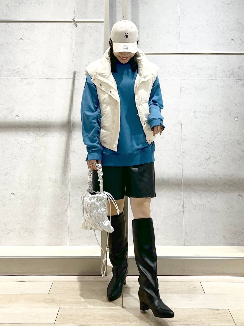 ホワイト系のダウンベスト、シルバー系のショルダーバッグ、ブラック系のその他パンツを着用したレディースの冬コーディネートの6枚目の写真