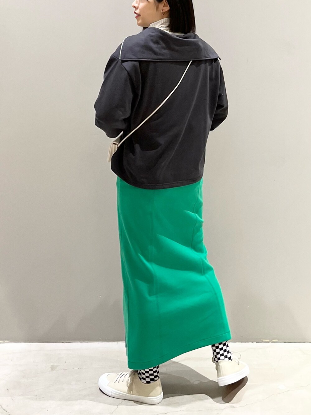 グリーン系のスカート、ベージュ系のスニーカー、ホワイト系のショルダーバッグを着用したレディースの春コーディネートの3枚目の写真