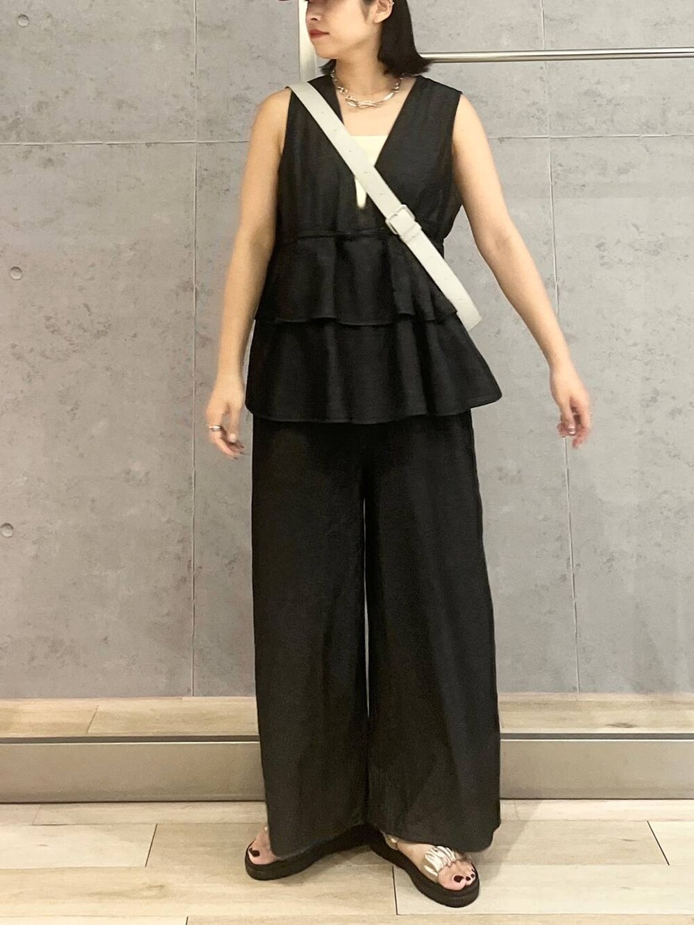 ホワイト系のタンクトップ、ベージュ系のサンダル、ブラック系のつなぎ/オールインワンを着用したレディースの夏コーディネートの3枚目の写真