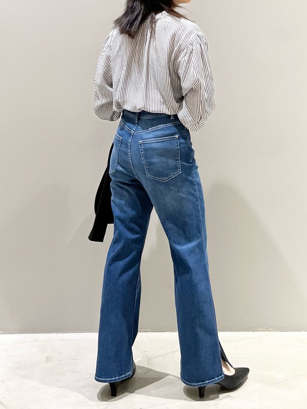 ブルー系のデニムパンツ、ブラック系のパンプス、ホワイト系のショルダーバッグを着用したレディースの秋コーディネートの4枚目の写真