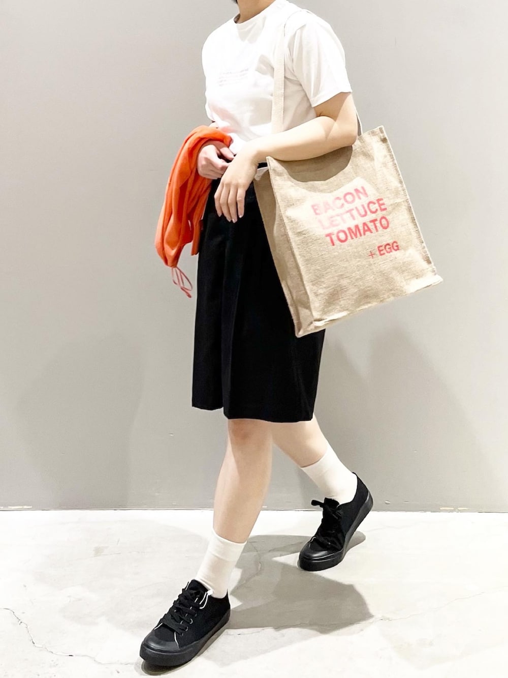 ブラック系のその他パンツ、ブラック系のスニーカー、オレンジ系のトートバッグを着用したレディースの夏コーディネートの5枚目の写真