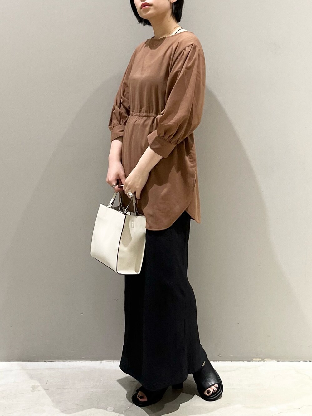 イエロー系のシャツ/ブラウス、ブラック系のスカート、ブラウン系のバッグを着用したレディースの秋コーディネートの7枚目の写真