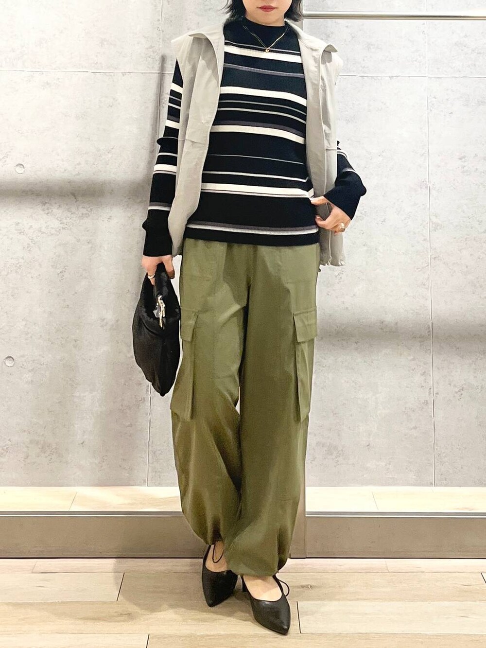 グレー系のベスト、ブラック系のハンドバッグ、グリーン系のカーゴパンツを着用したレディースの冬コーディネートの9枚目の写真