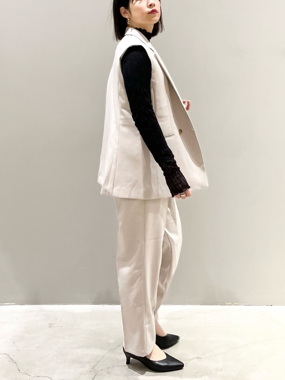 ブラック系のパンプス、ベージュ系のスラックス、ブラック系のハンドバッグを着用したレディースの冬コーディネートの3枚目の写真