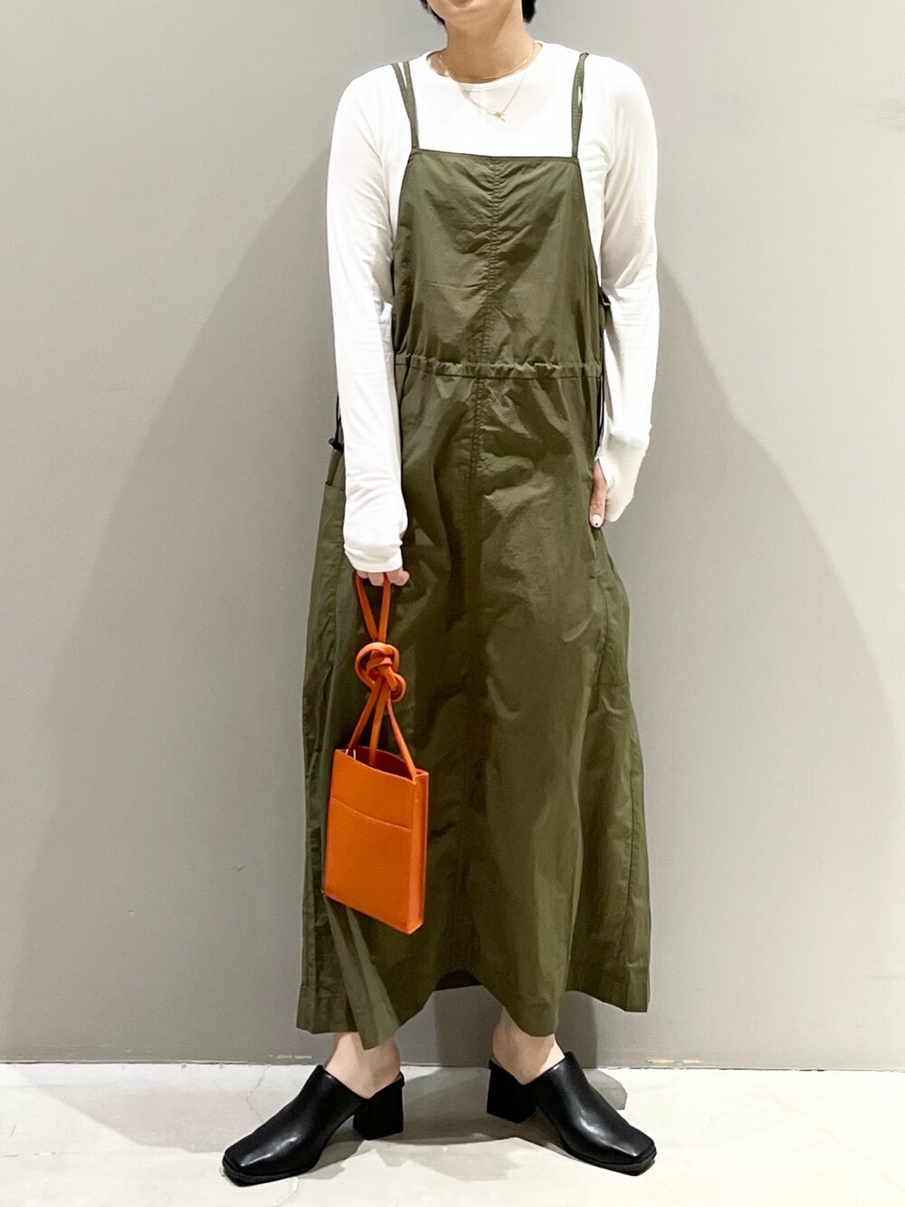 グリーン系のワンピース、オレンジ系のバッグ、ブラック系のサンダルを着用したレディースの春コーディネートの6枚目の写真