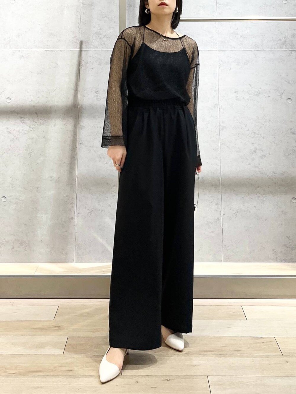 シルバー系のハンドバッグ、ブラック系のシャツ/ブラウス、ブラック系のスラックスを着用したレディースの冬コーディネートの2枚目の写真