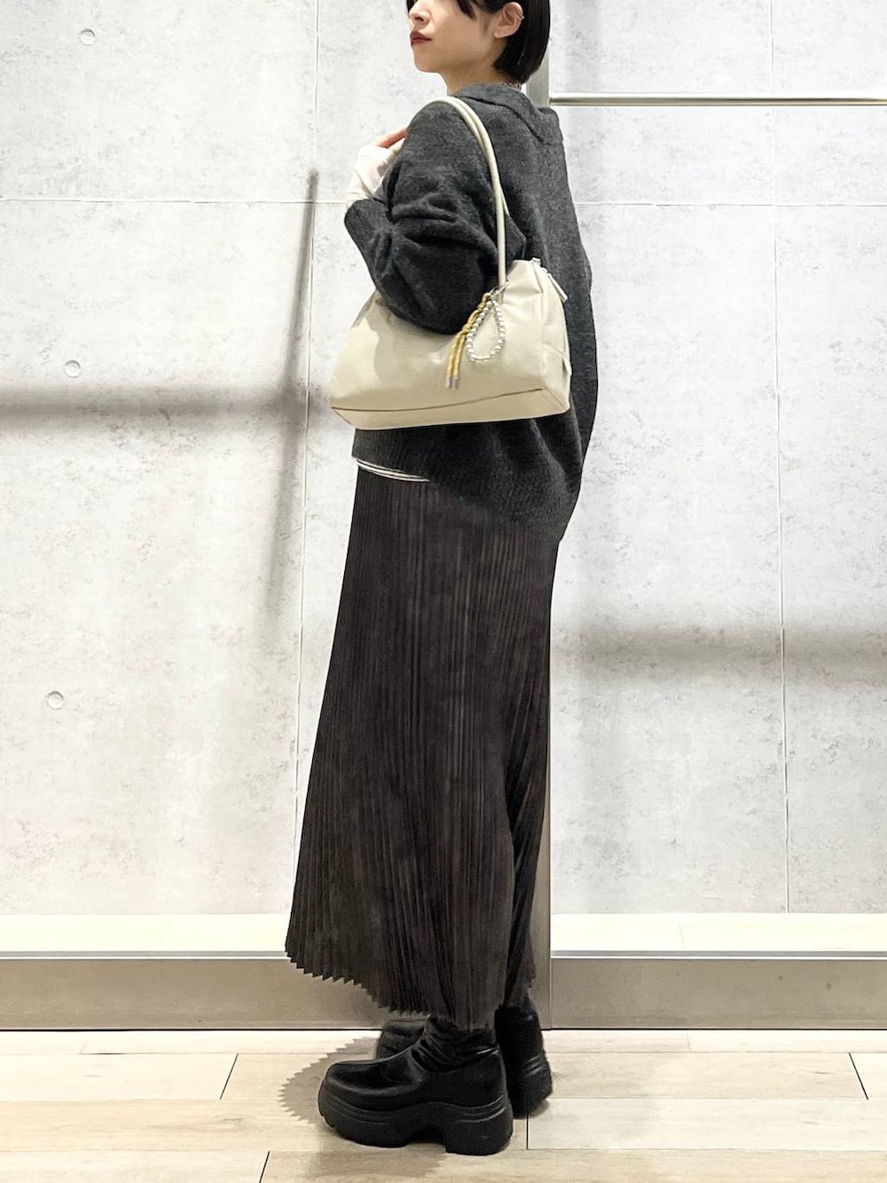 ホワイト系のTシャツ/カットソー、グレー系のスカート、ブラック系のブーツを着用したレディースの冬コーディネートの2枚目の写真