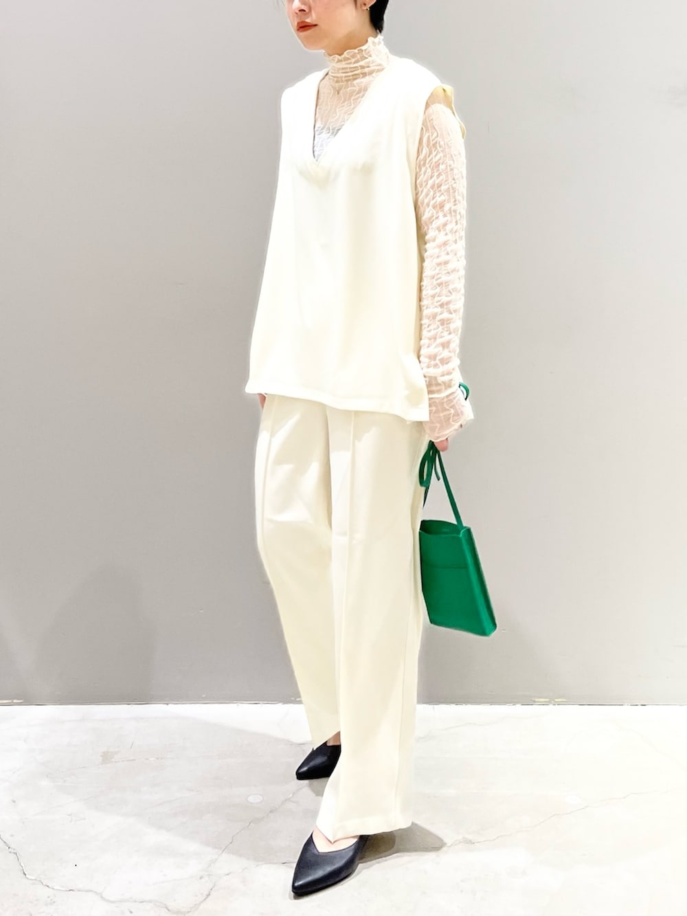 ホワイト系のベスト、グレー系のシューズ、グリーン系のバッグを着用したレディースの夏コーディネートの5枚目の写真