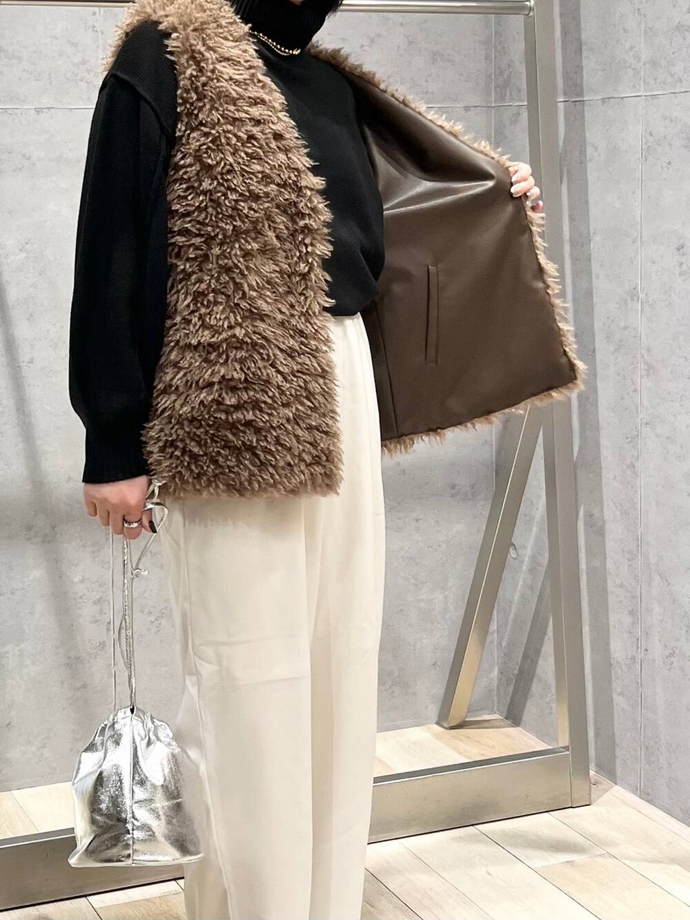 ブラック系のニット/セーター、ブラウン系のブーツ、ホワイト系のその他パンツを着用したレディースの秋コーディネートの5枚目の写真