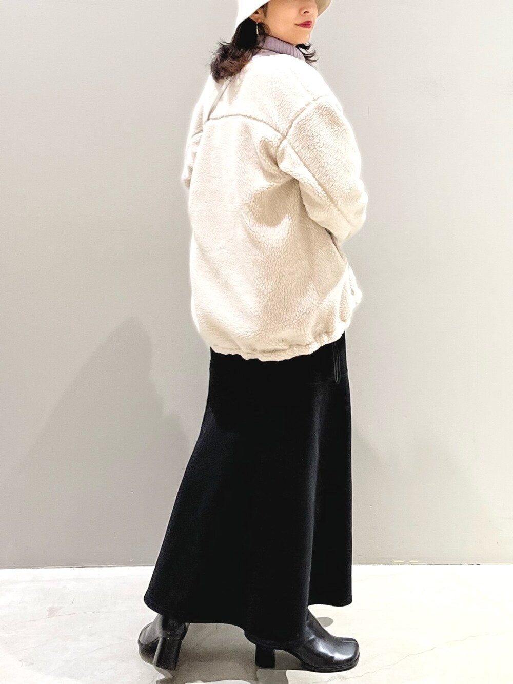 ブラック系のスカート、ブラック系のブーツ、ホワイト系のノーカラージャケットを着用したレディースの冬コーディネートの3枚目の写真