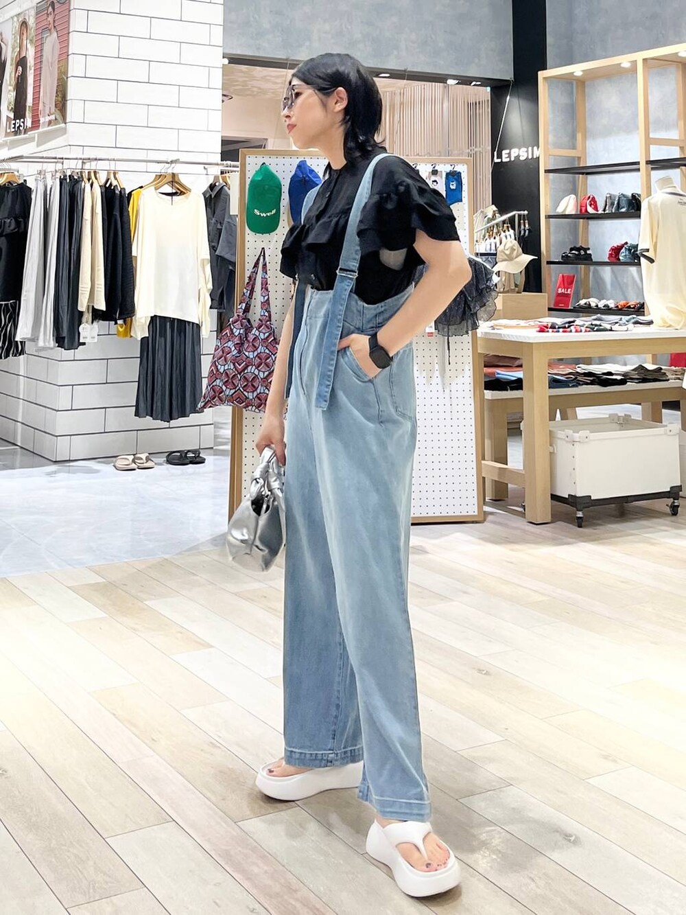 ホワイト系のサンダル、ブルー系のデニムパンツ、シルバー系のショルダーバッグを着用したレディースの夏コーディネートの6枚目の写真