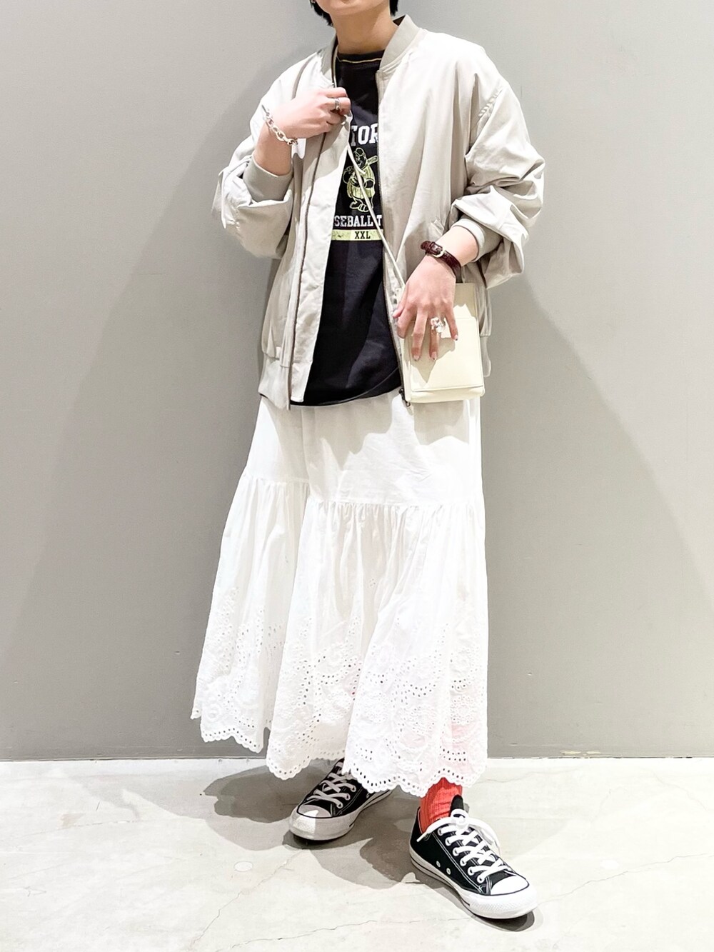 ブラック系のスニーカー、ホワイト系のスカート、ホワイト系のショルダーバッグを着用したレディースの春コーディネートの3枚目の写真