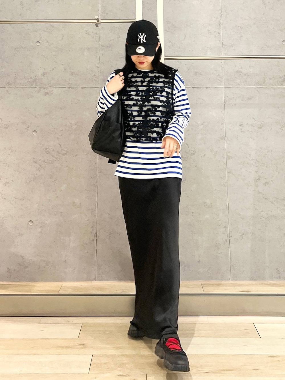 ブラック系のスカート、ブルー系のTシャツ/カットソー、ブラック系のスニーカーを着用したレディースの冬コーディネートの3枚目の写真