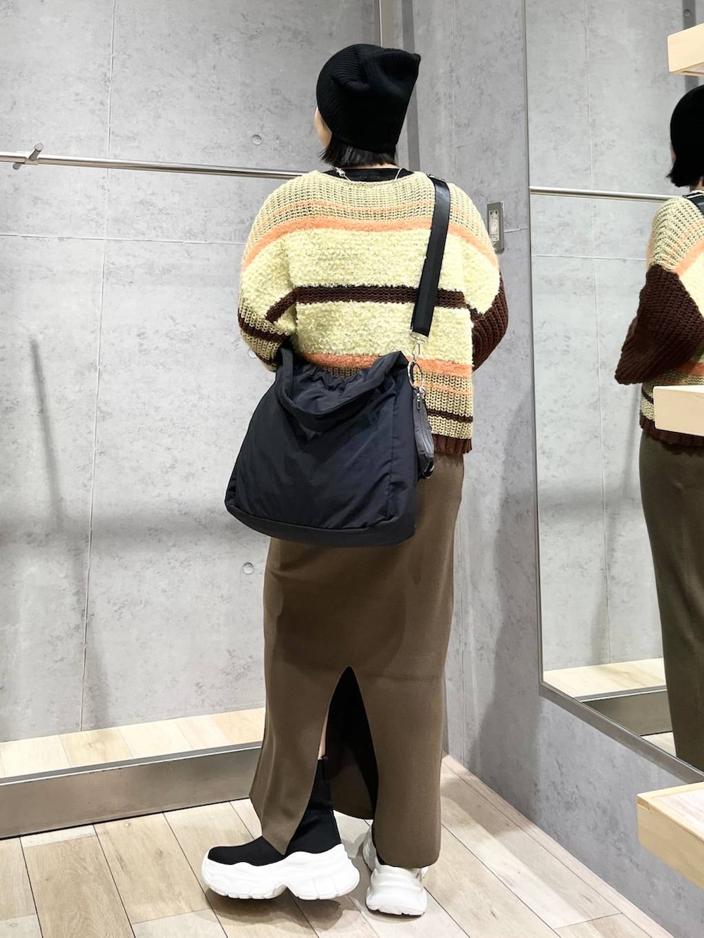 ブラウン系のスカート、ブラウン系のニット/セーター、ブラック系のブーツを着用したレディースの秋コーディネートの5枚目の写真