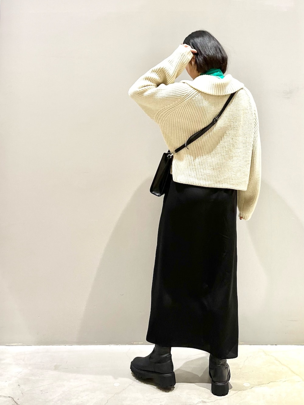 ブラック系のスカート、ブラック系のショルダーバッグ、ブラック系のブーツを着用したレディースの冬コーディネートの3枚目の写真