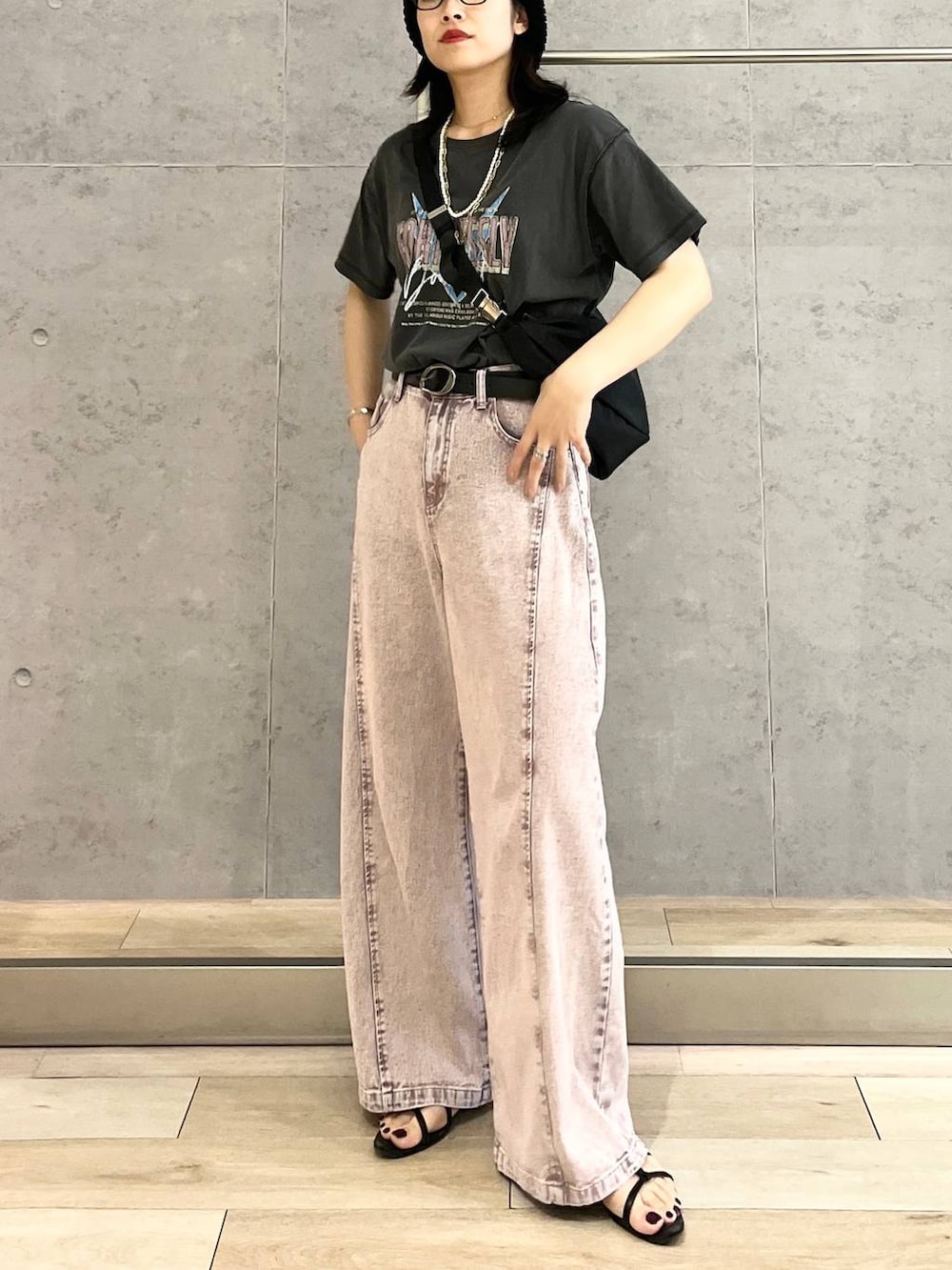 パープル系のデニムパンツ、ブラック系のショルダーバッグ、ブラック系のTシャツ/カットソーを着用したレディースの春コーディネートの2枚目の写真