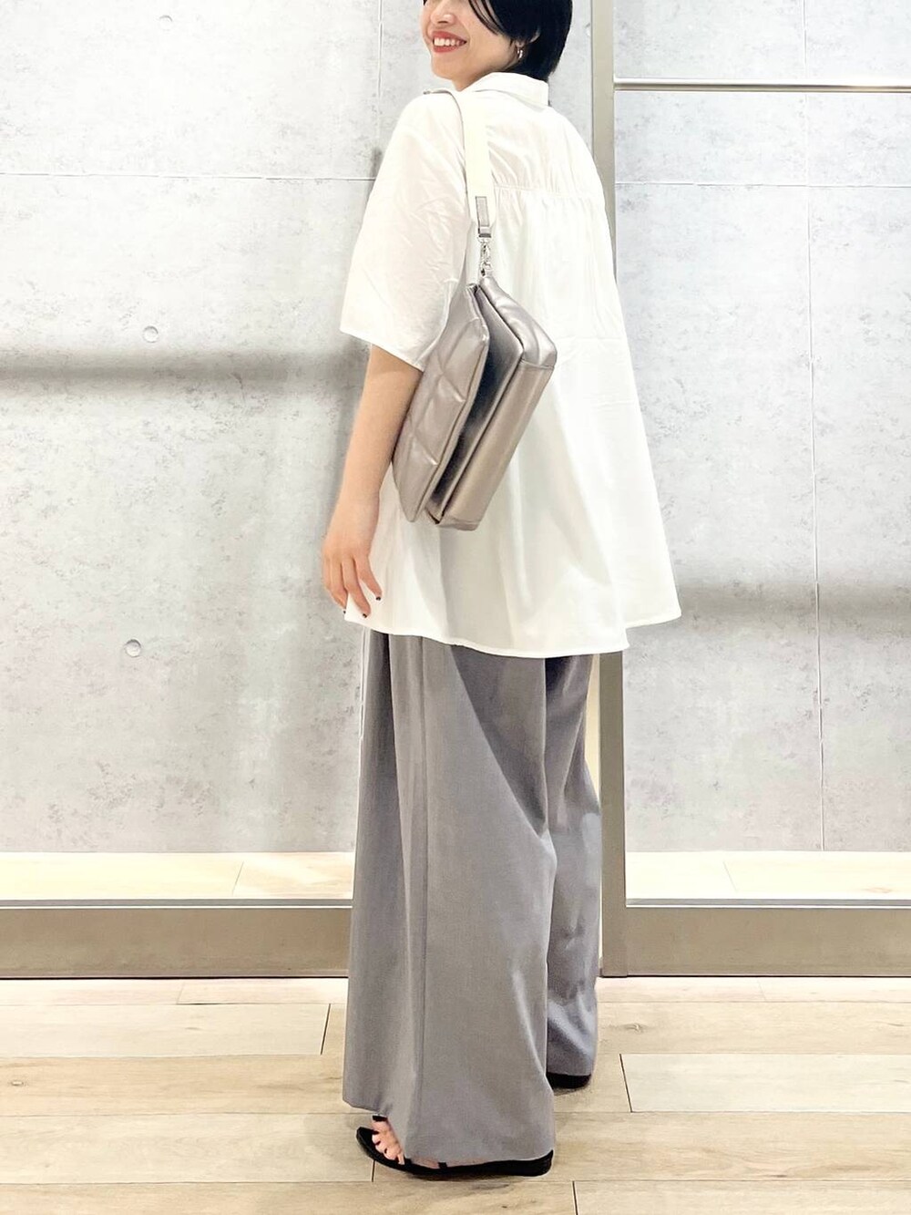 ブラック系のサンダル、ブラック系のハンドバッグ、グレー系のスラックスを着用したレディースの夏コーディネートの4枚目の写真