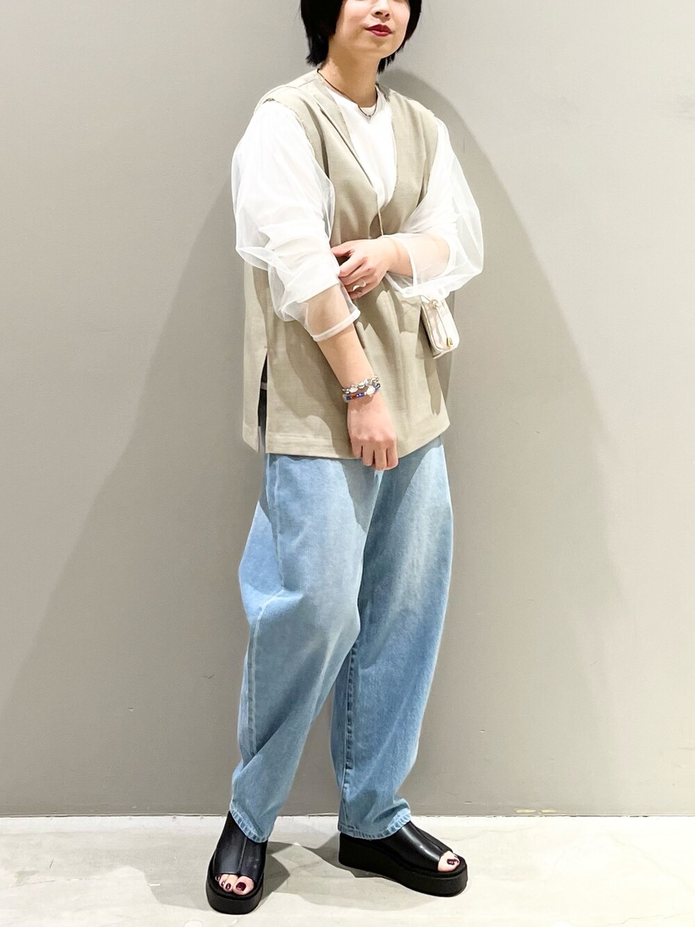 ブルー系のデニムパンツ、ホワイト系のサンダル、ブラック系のバッグを着用したレディースの春コーディネートの5枚目の写真