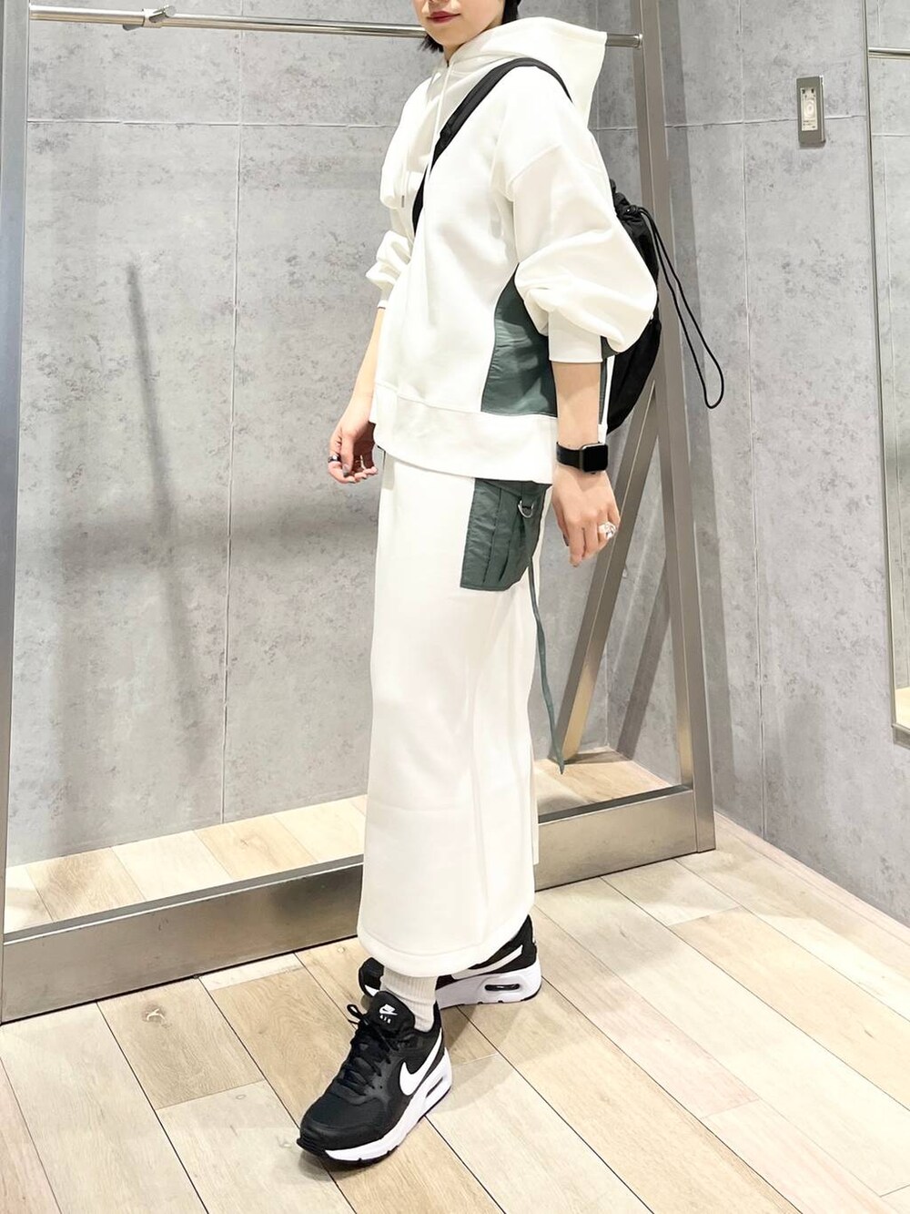 ブラック系のショルダーバッグ、ホワイト系のスカート、ホワイト系のパーカーを着用したレディースの冬コーディネートの8枚目の写真