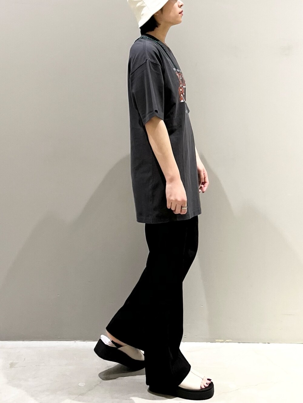 ブラック系のパンツ、ホワイト系のサンダル、グリーン系のショルダーバッグを着用したレディースの秋コーディネートの7枚目の写真