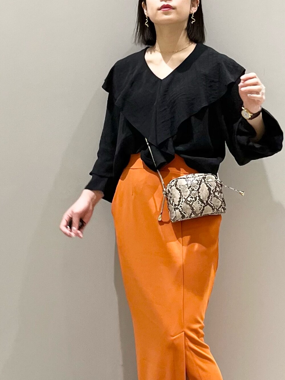 オレンジ系のスカート、ホワイト系のパンプス、その他のショルダーバッグを着用したレディースの春コーディネートの3枚目の写真