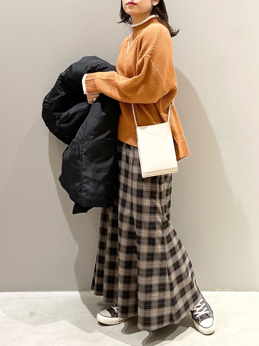 ブラック系のスカート、グレー系のスニーカー、ホワイト系のショルダーバッグを着用したレディースの冬コーディネートの3枚目の写真