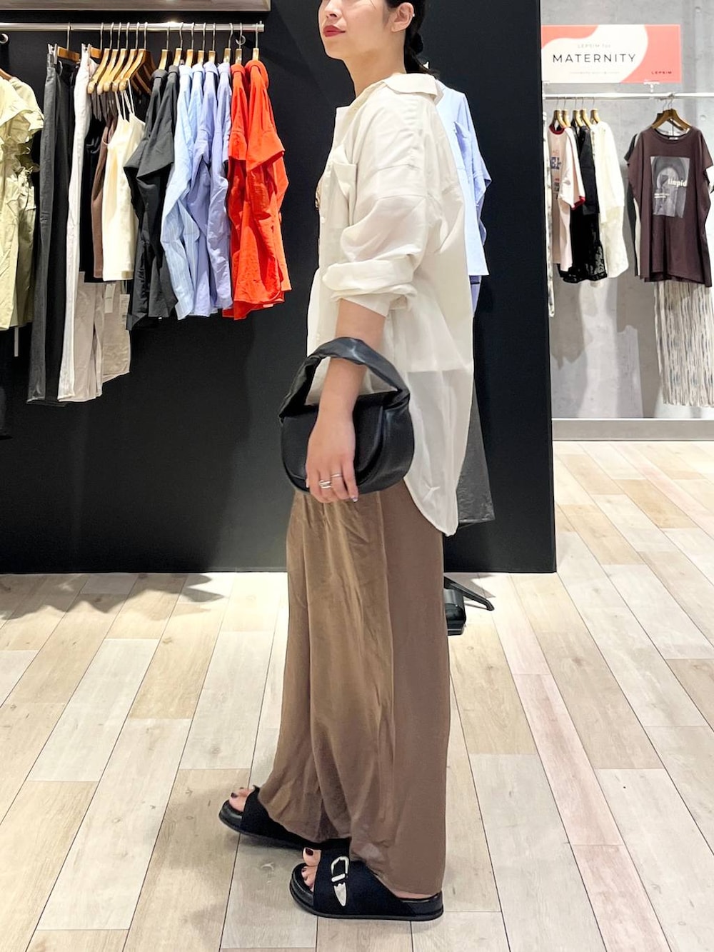 ブラック系のハンドバッグ、ブラック系のサンダル、ホワイト系のシャツ/ブラウスを着用したレディースの夏コーディネートの4枚目の写真