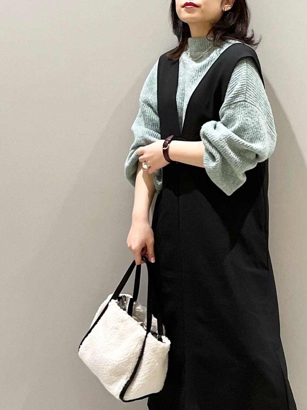 ホワイト系のバッグ、ブラック系のブーツ、グリーン系のニット/セーターを着用したレディースの冬コーディネートの5枚目の写真