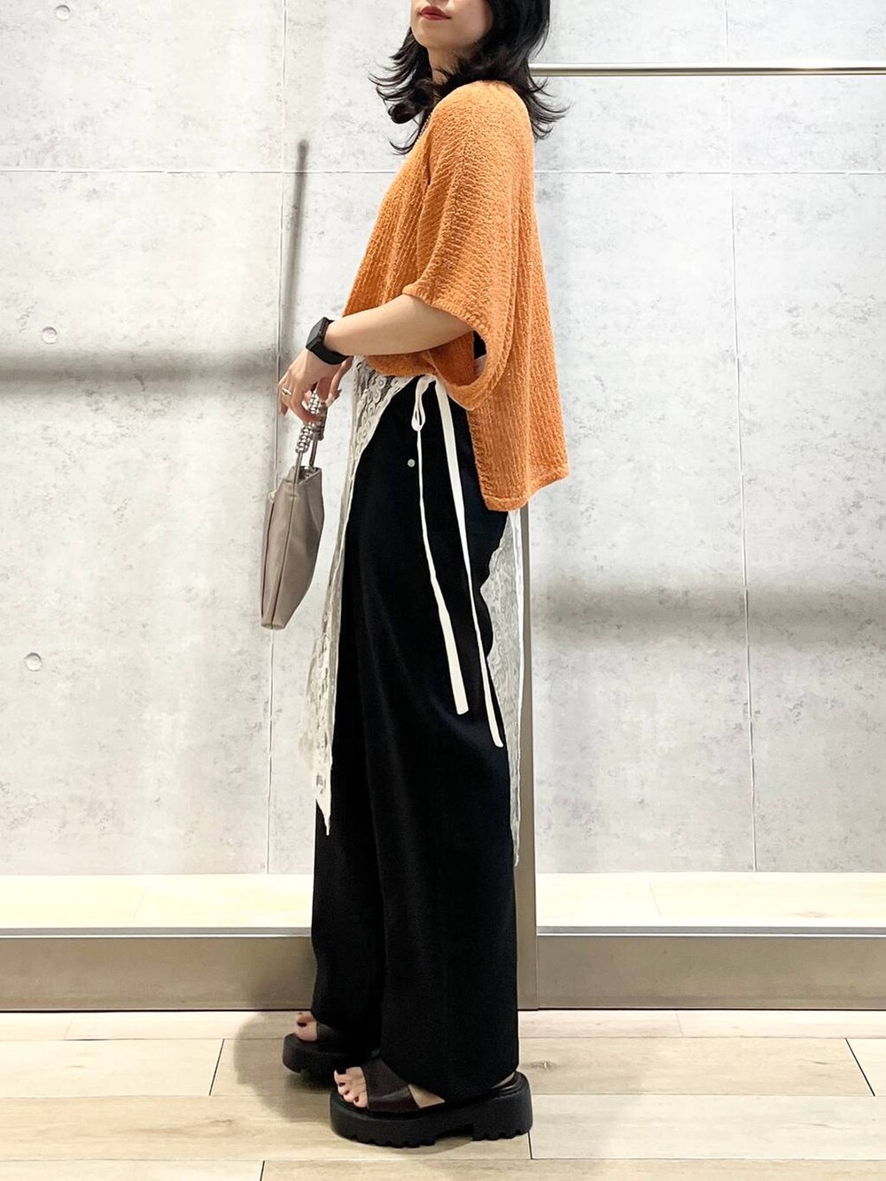 オレンジ系のニット/セーター、ブラック系のその他パンツ、ブラウン系のサンダルを着用したレディースの夏コーディネートの4枚目の写真