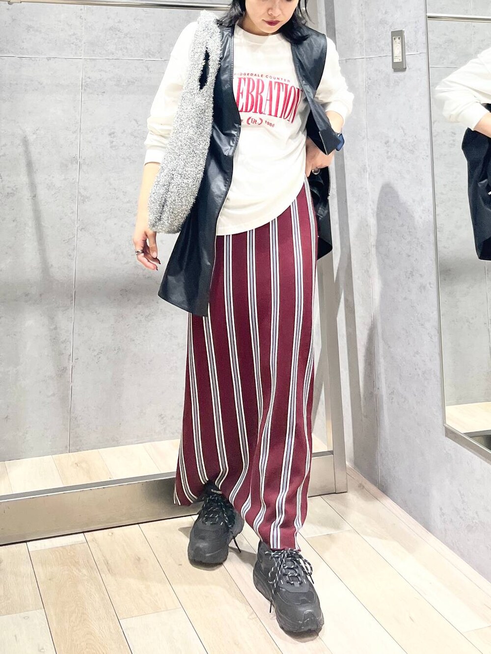 シルバー系のショルダーバッグ、レッド系のスカート、ブラック系のワンピースを着用したレディースの秋コーディネートの2枚目の写真