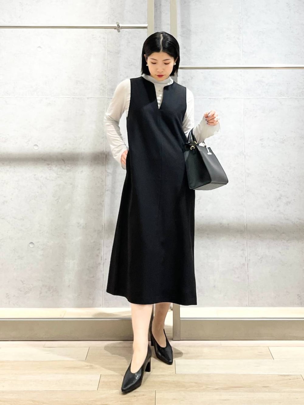 ブラック系のパンプス、グレー系のTシャツ/カットソー、ブラック系のショルダーバッグを着用したレディースの冬コーディネートの2枚目の写真