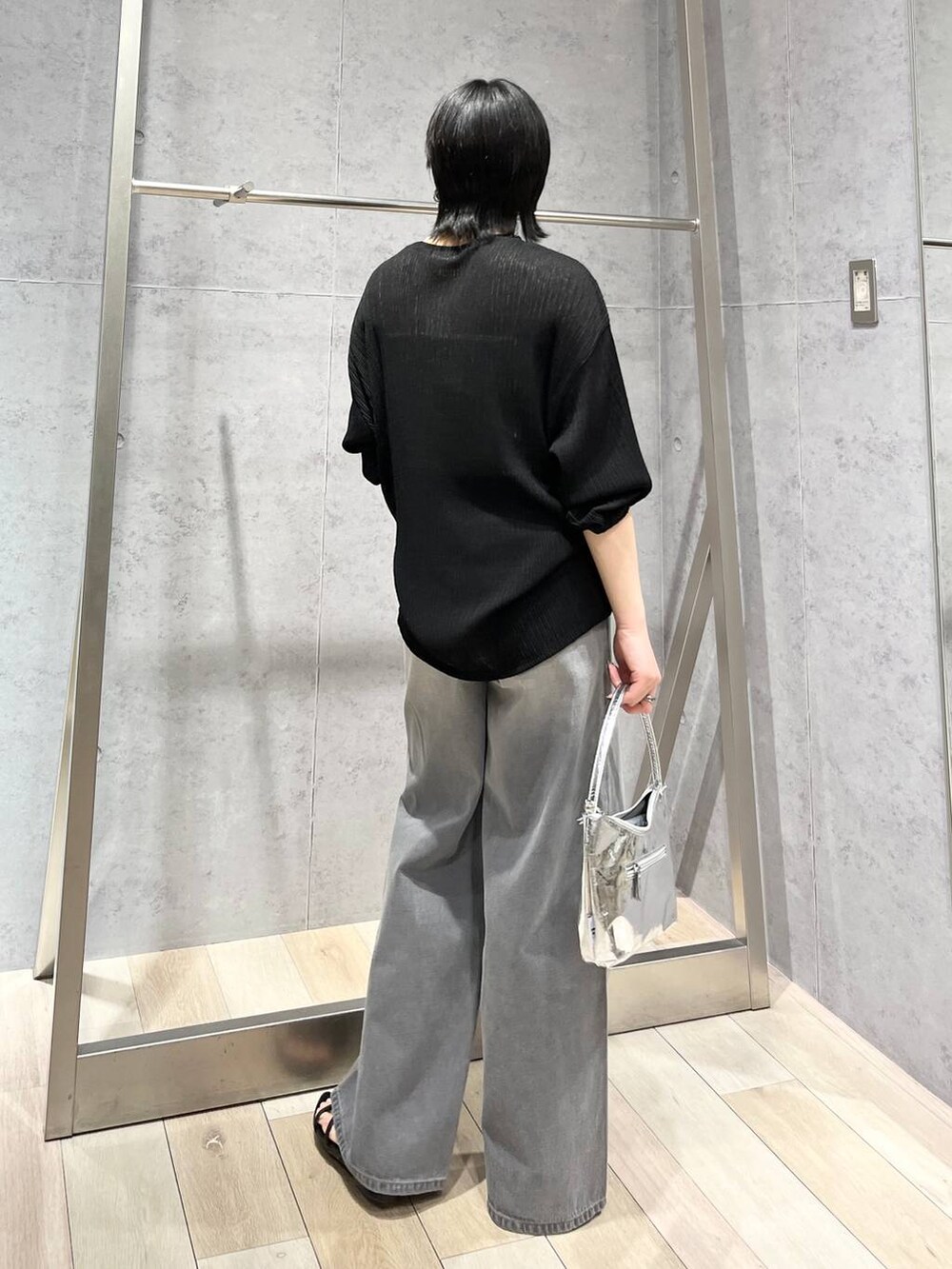 シルバー系のハンドバッグ、ブラック系のサンダル、グレー系のデニムパンツを着用したレディースの春コーディネートの7枚目の写真