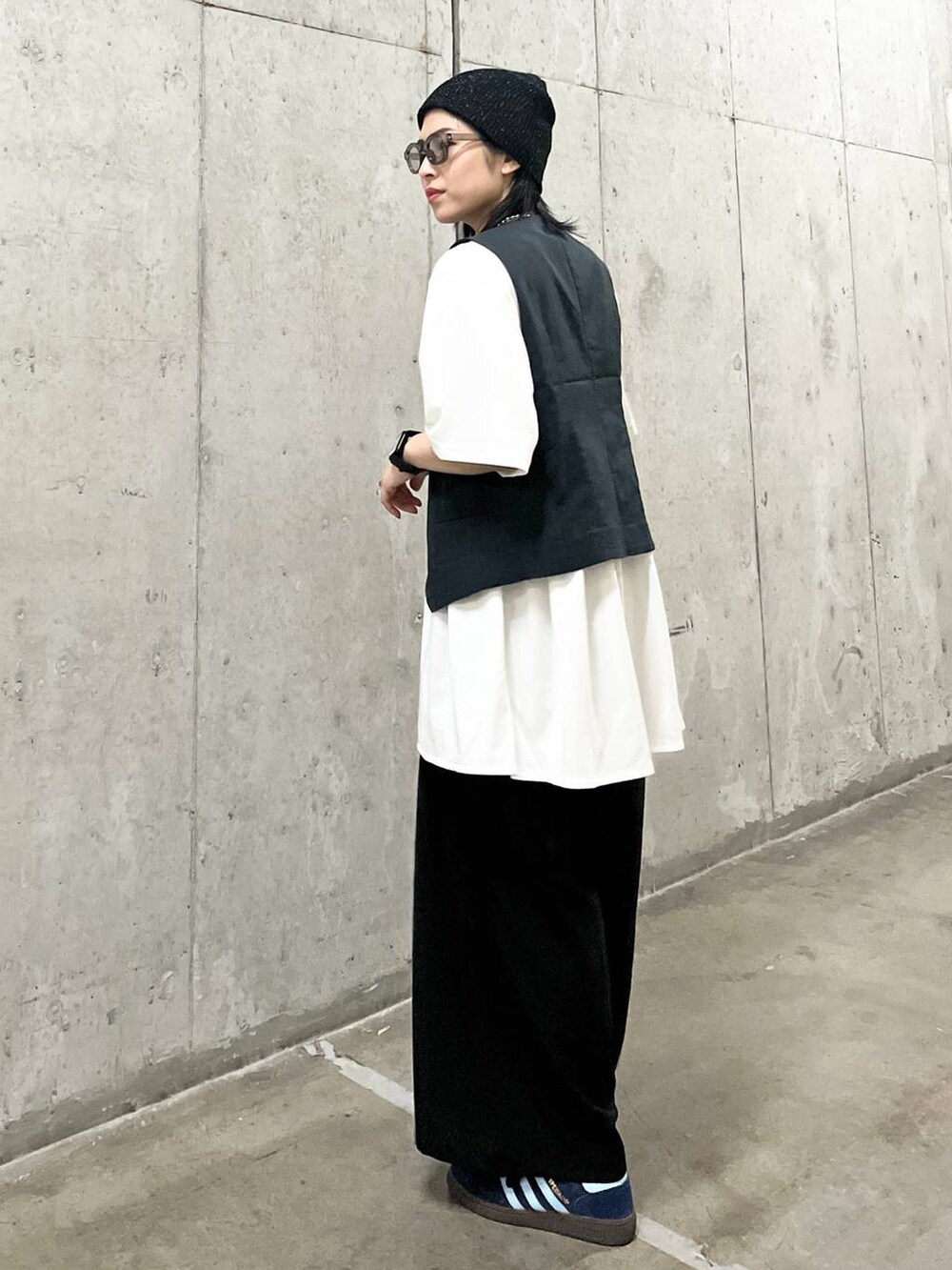 ブラック系のスラックス、ブラック系のショルダーバッグ、グレー系のベストを着用したレディースの夏コーディネートの4枚目の写真