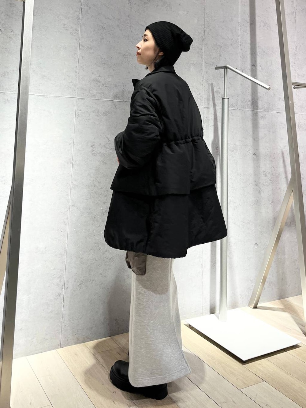 グレー系のスカート、ブラック系のボストンバッグ、ブラック系のブーツを着用したレディースの秋コーディネートの5枚目の写真