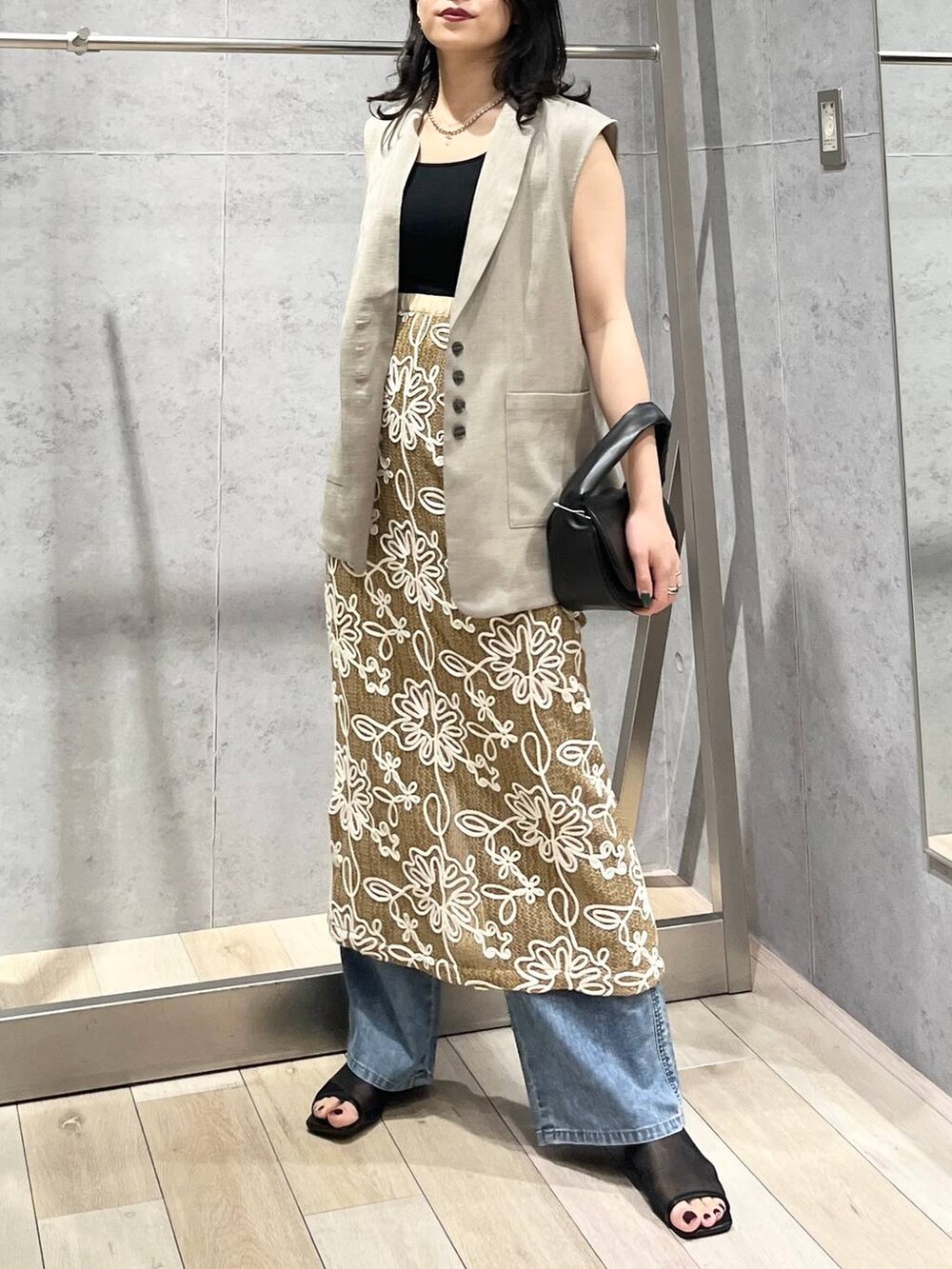 ブルー系のデニムパンツ、ブラック系のハンドバッグ、ブラック系のサンダルを着用したレディースの春コーディネートの2枚目の写真
