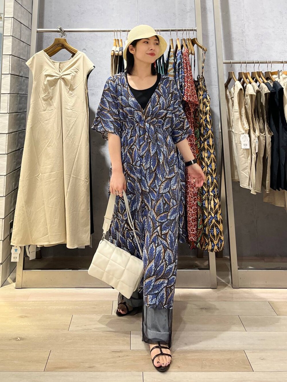 ホワイト系のショルダーバッグ、ブラック系のサンダル、ブルー系のデニムパンツを着用したレディースの夏コーディネートの2枚目の写真