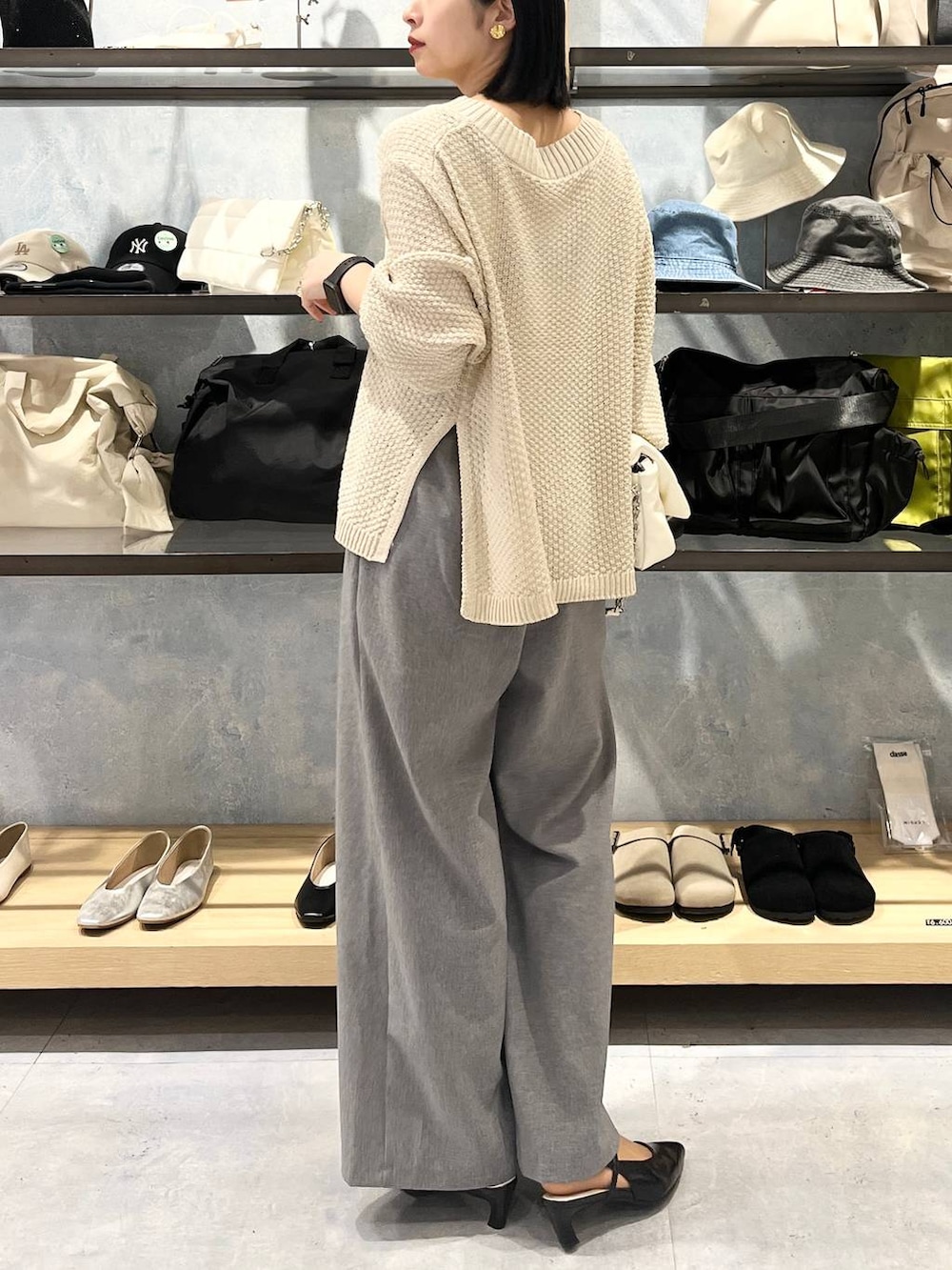 ホワイト系のショルダーバッグ、ホワイト系のニット/セーター、グレー系のスラックスを着用したレディースの春コーディネートの2枚目の写真