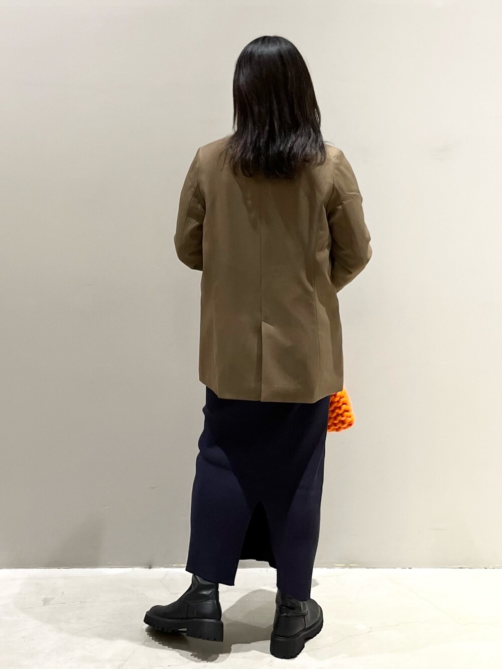 ブラック系のブーツ、ブルー系のスカート、オレンジ系のショルダーバッグを着用したレディースの秋コーディネートの3枚目の写真