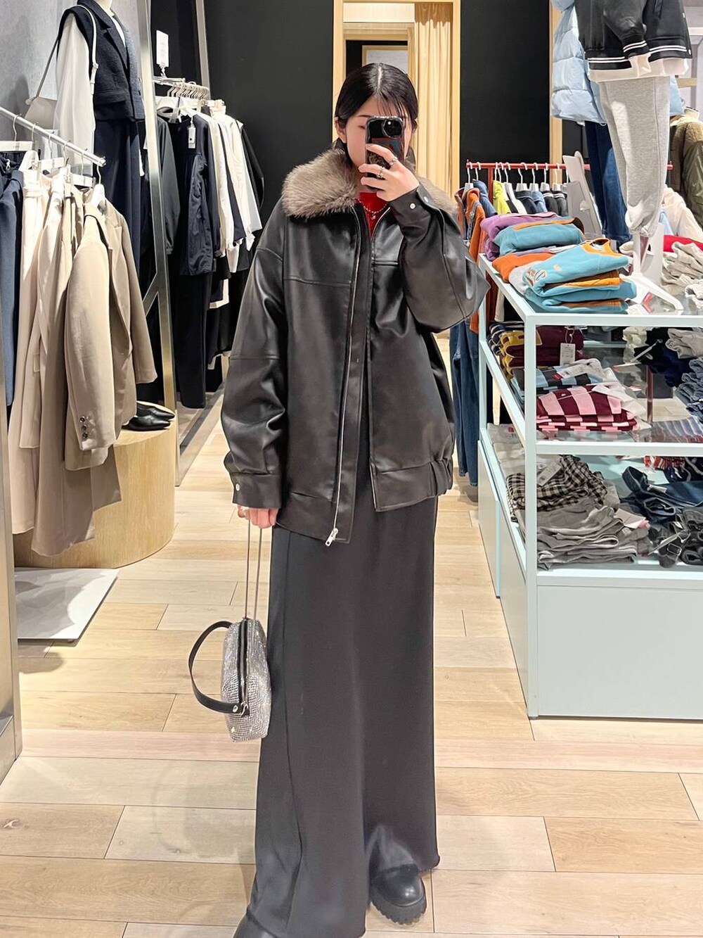 ブラック系のブーツ、オレンジ系のニット/セーター、ブラック系のスカートを着用したレディースの冬コーディネートの9枚目の写真